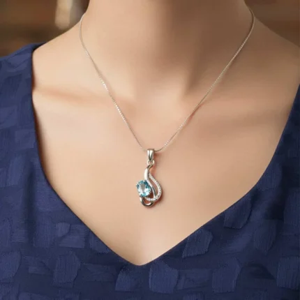 model wearing silver pendant with 5x7 mm oval blue topaz