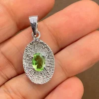 silver pendant with 5x7 mm oval peridot displayed on hand
