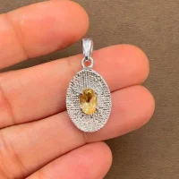 silver pendant with 5x7 mm oval citrine displayed on hand