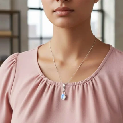 model wearing silver pendant with 5x7 mm oval rainbow moonstone