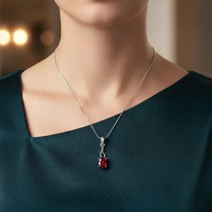 model wearing silver pendant with 5x7 mm oval garnet