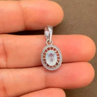 silver pendant with 5x7 mm oval rainbow moonstone displayed on hand
