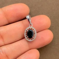 silver pendant with 5x7 mm oval black onyx displayed on hand