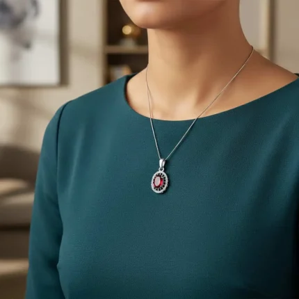 model wearing silver pendant with 5x7 mm oval garnet