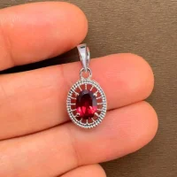 silver pendant with 5x7 mm oval garnet displayed on hand