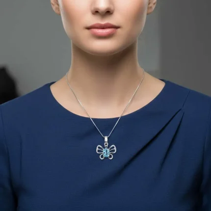 model wearing silver pendant butterfly shaped with 5x7 mm oval blue topaz