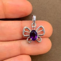 silver pendant butterfly shaped with 5x7 mm oval amethyst displayed on hand