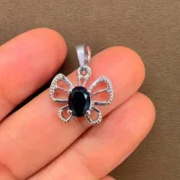 silver pendant butterfly shaped with 5x7 mm oval black onyx displayed on hand