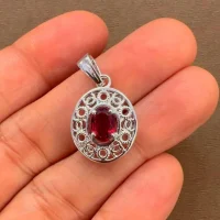 silver pendant with 5x7 mm oval garnet displayed on hand