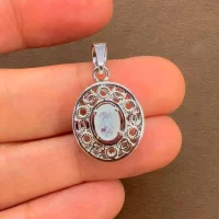 silver pendant with 5x7 mm oval rainbow moonstone displayed on hand