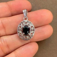 silver pendant with 5x7 mm oval black onyx displayed on hand