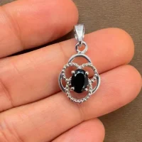 silver pendant with 5x7 mm oval black onyx displayed on hand