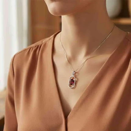 model wearing silver pendant with 5x7 mm oval garnet