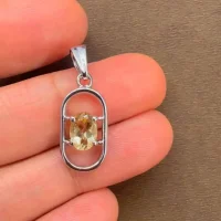 silver pendant with 5x7 mm oval citrine displayed on hand