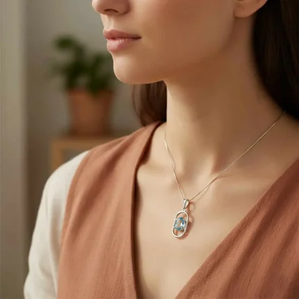 model wearing silver pendant with 5x7 mm oval blue topaz