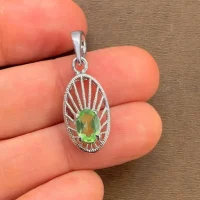silver pendant with 5x7 mm oval peridot displayed on hand