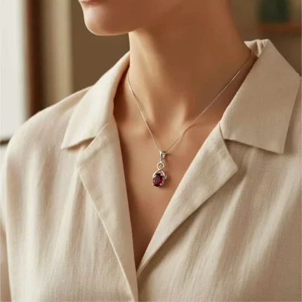model wearing silver pendant with 5x7 mm oval garnet