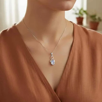 model wearing silver pendant with 5x7 mm oval rainbow moonstone