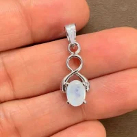 silver pendant with 5x7 mm oval rainbow moonstone displayed on hand