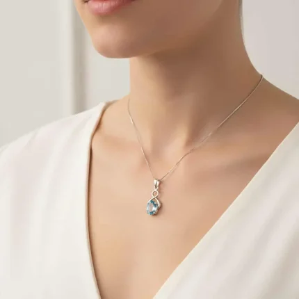 model wearing silver pendant with 5x7 mm oval blue topaz