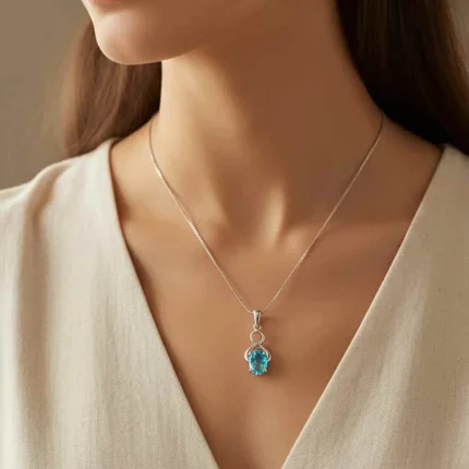 model wearing silver pendant with 5x7 mm oval swiss blue topaz
