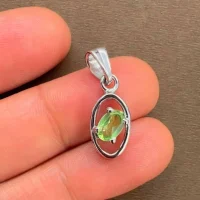 silver pendant with 6x4 mm oval peridot displayed on hand
