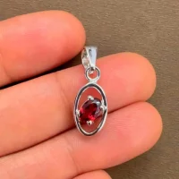 silver pendant with 6x4 mm oval garnet displayed on hand