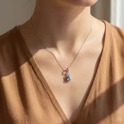 model wearing silver pendant with 6x4 mm pear blue topaz