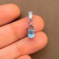 silver pendant with 6x4 mm pear blue topaz displayed on hand