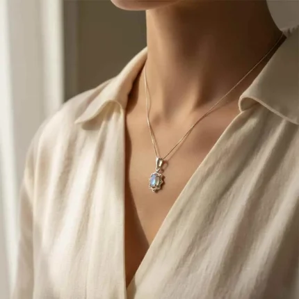 model wearing silver pendant with 6x4 mm oval rainbow moonstone