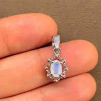 silver pendant with 6x4 mm oval rainbow moonstone displayed on hand