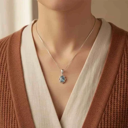 model wearing silver pendant with 6x4 mm oval blue topaz