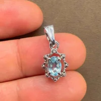 silver pendant with 6x4 mm oval blue topaz displayed on hand