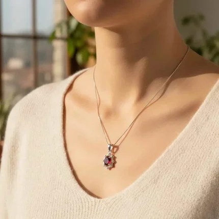 model wearing silver pendant with 6x4 mm oval garnet