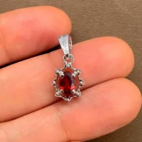 silver pendant with 6x4 mm oval garnet displayed on hand