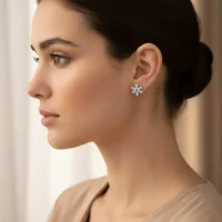 model wearing silver studs snowflake design with 5 mm round blue topaz in band setting and cubic zirconia in prong setting