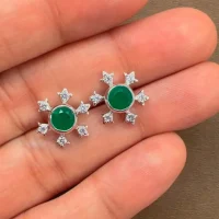 silver studs snowflake design with 5 mm round green onyx in band setting and cubic zirconia in prong setting displayed o hand