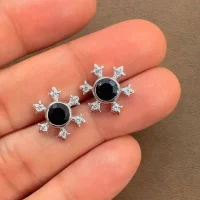 silver studs snowflake design with 5 mm round black onyx in band setting and cubic zirconia in prong setting displayed on hand