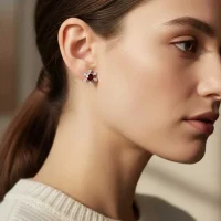 model wearing silver studs snowflake design with 5 mm round garnet in band setting and cubic zirconia in prong setting