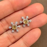 silver studs snowflake design with 5 mm round citrine in band setting and cubic zirconia in prong setting displayed on hand