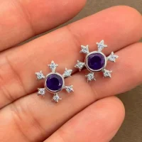 silver studs snowflake design with 5 mm round amethyst in band setting and cubic zirconia in prong setting displayed on hand