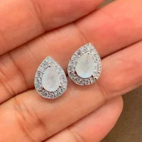 silver studs cluster with 7x5 mm pear Rainbow Moonstone and cubic zirconia displayed on hand