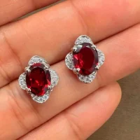 silver studs with 7x9 mm oval Garnet and cubic zirconia displayed on hand