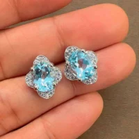 silver studs with 7x9 mm oval Blue Topaz and cubic zirconia displayed on hand