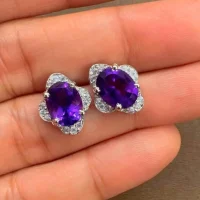 silver studs with 7x9 mm oval Amethyst and cubic zirconia displayed on hand