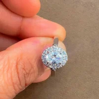 Silver Ring cluster with 5x7 mm oval shaped Cubic Zirconia and small round Cubic Zirconia displayed on hand