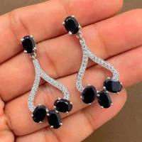 Silver Earrings with 5x7 mm oval shaped Black Onyx Gemstone and Cubic Zirconia displayed on hand