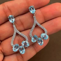 5x7 mm oval shaped Blue Topaz Gemstone and Cubic Zirconia displayed on hand