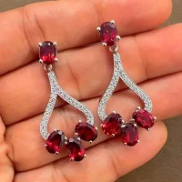 5x7 mm oval shaped Garnet Gemstone and Cubic Zirconia displayed on hand