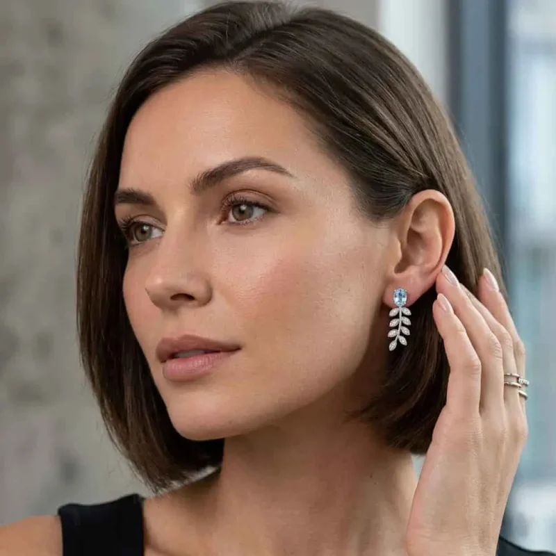 model wearing silver earrings gemstones with 5x7 mm oval blue topaz